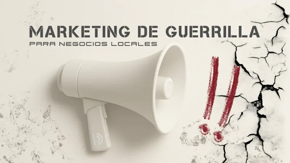 Imagen en tonos neutros que muestra un megáfono blanco apuntando hacia la derecha. A su lado, la pared aparece resquebrajada y con marcas rojas de exclamación dibujadas a mano, simbolizando el impacto y la disrupción del marketing de guerrilla. En la parte superior se lee “Marketing de guerrilla para negocios locales” con tipografía estilo stencil.