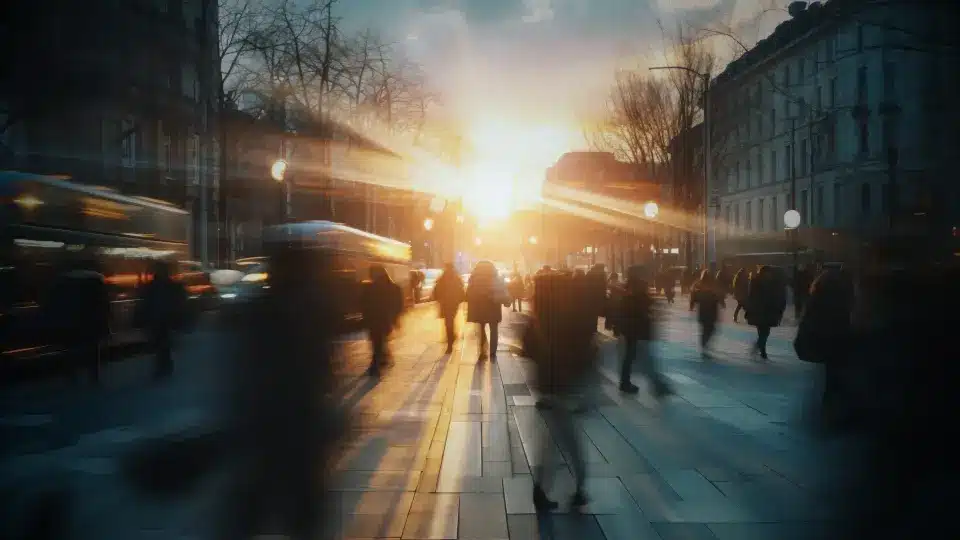 Escena urbana difuminada al atardecer con personas y vehículos en movimiento rápido, evocando la vitalidad de la ciudad y el dinámico entorno donde tu negocio local en Zaragoza puede prosperar con el marketing adecuado.